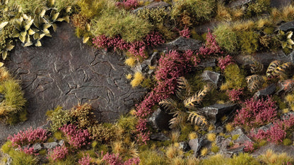 Miniature diorama of a rocky landscape with carved animals, green grass, and purple heather