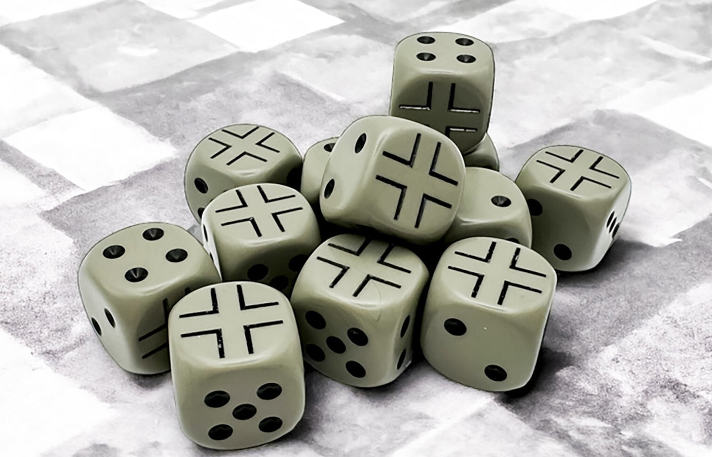 A pile of dark grey dice on a textured grey background. Some show pips, others black Iron Crosses