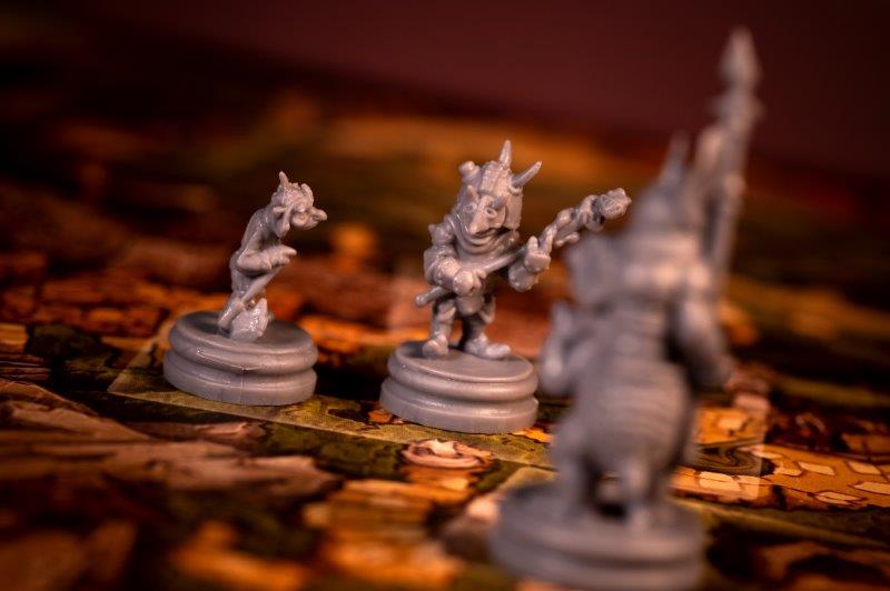 Two gray goblin board game miniatures on a game map, one holding a staff. A third is blurred.