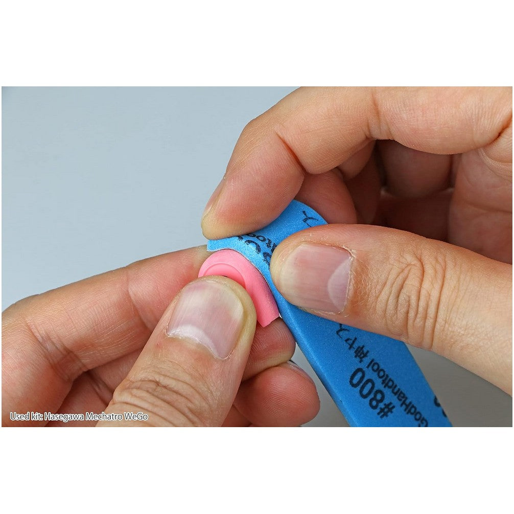 Close-up of hands sanding a pink plastic model part with a blue sanding tool