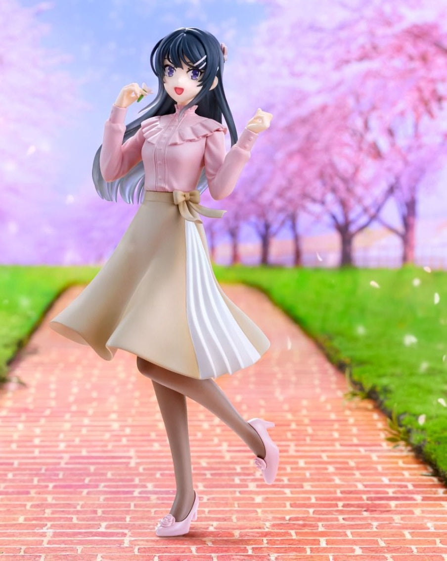 Anime figurine in pink and beige, smiling and holding a petal on a brick path with cherry blossoms