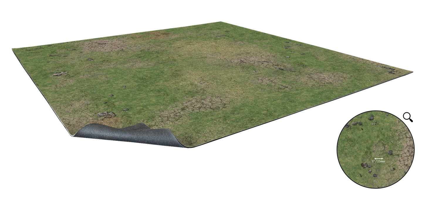 A rectangular game mat with dry grassy terrain and scattered rocks, corner lifted to show rubber underside. Inset with 1" scale.