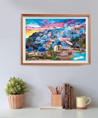 A vibrant framed print of a picturesque Greek village with white buildings, blue domes, and a windmill at sunset, above a desk.