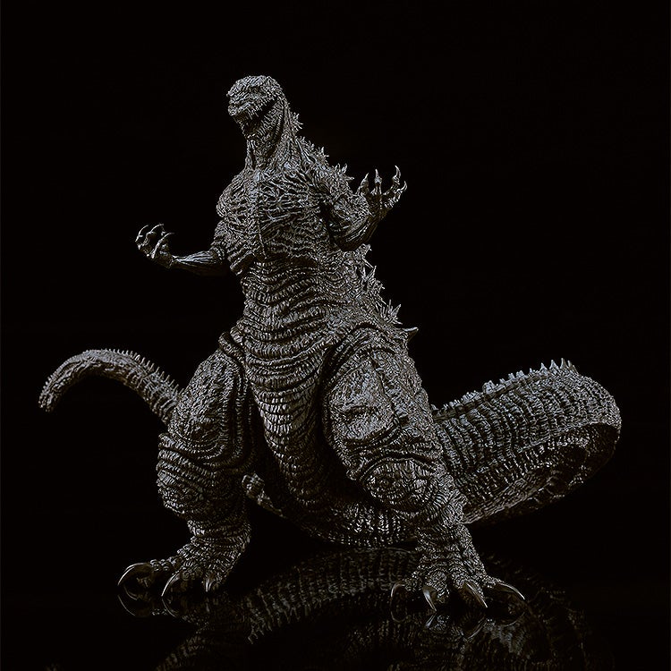 Highly detailed black Godzilla action figure with intricate textured skin and raised dorsal fins standing on a reflective surface
