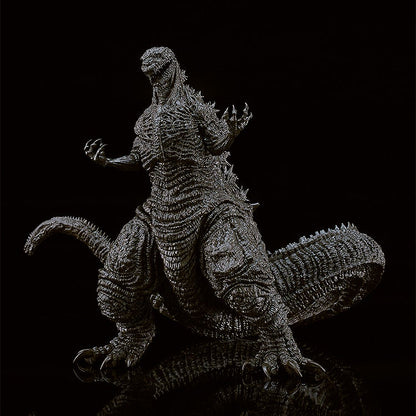 Highly detailed black Godzilla action figure with intricate textured skin and raised dorsal fins standing on a reflective surface