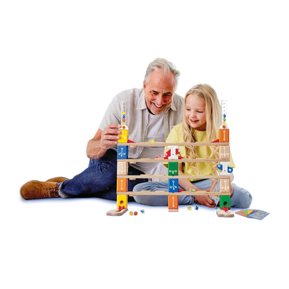 Smiling man and girl playing a colorful wooden marble game on the floor