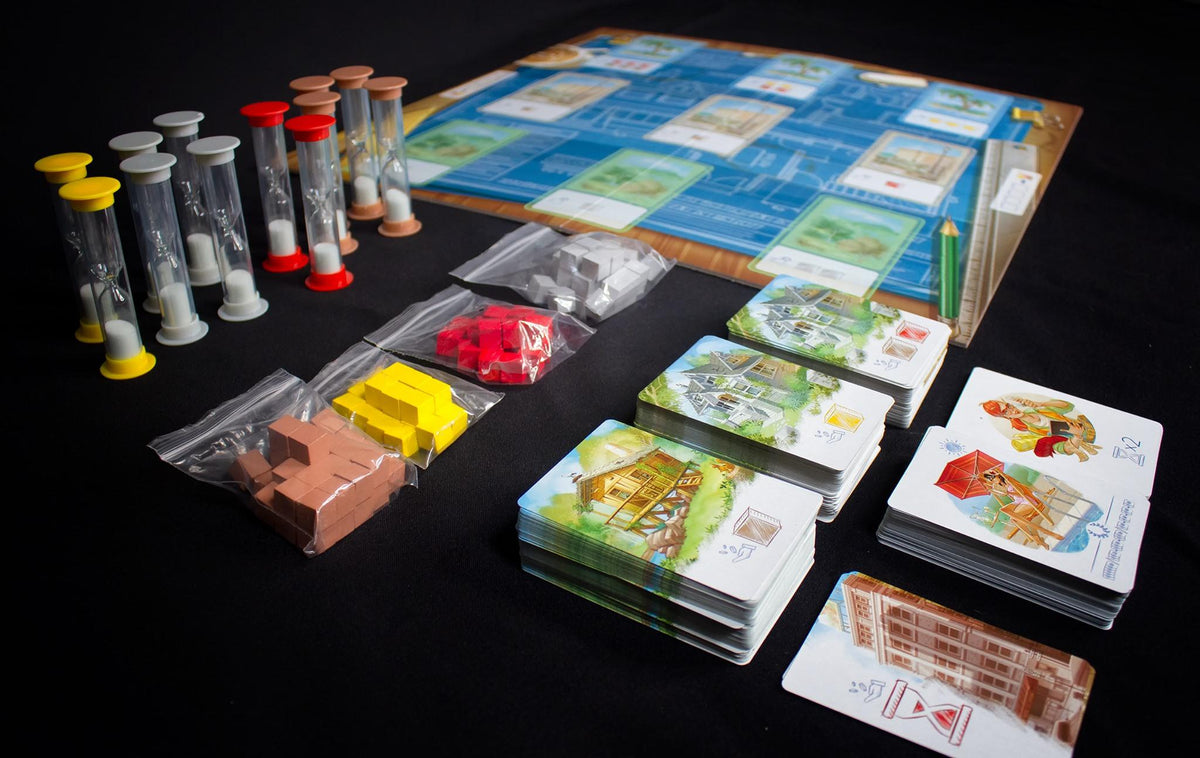 Board game layout featuring Hourglass with sand cards and building block pieces laid out on a black surface