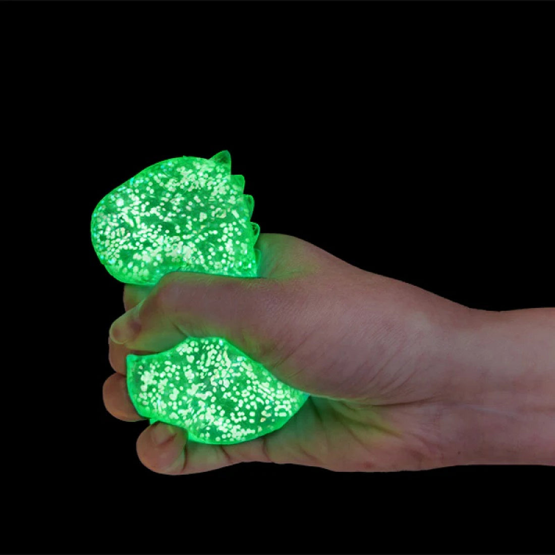 Hand squeezing a speckled, glow-in-the-dark green stress toy