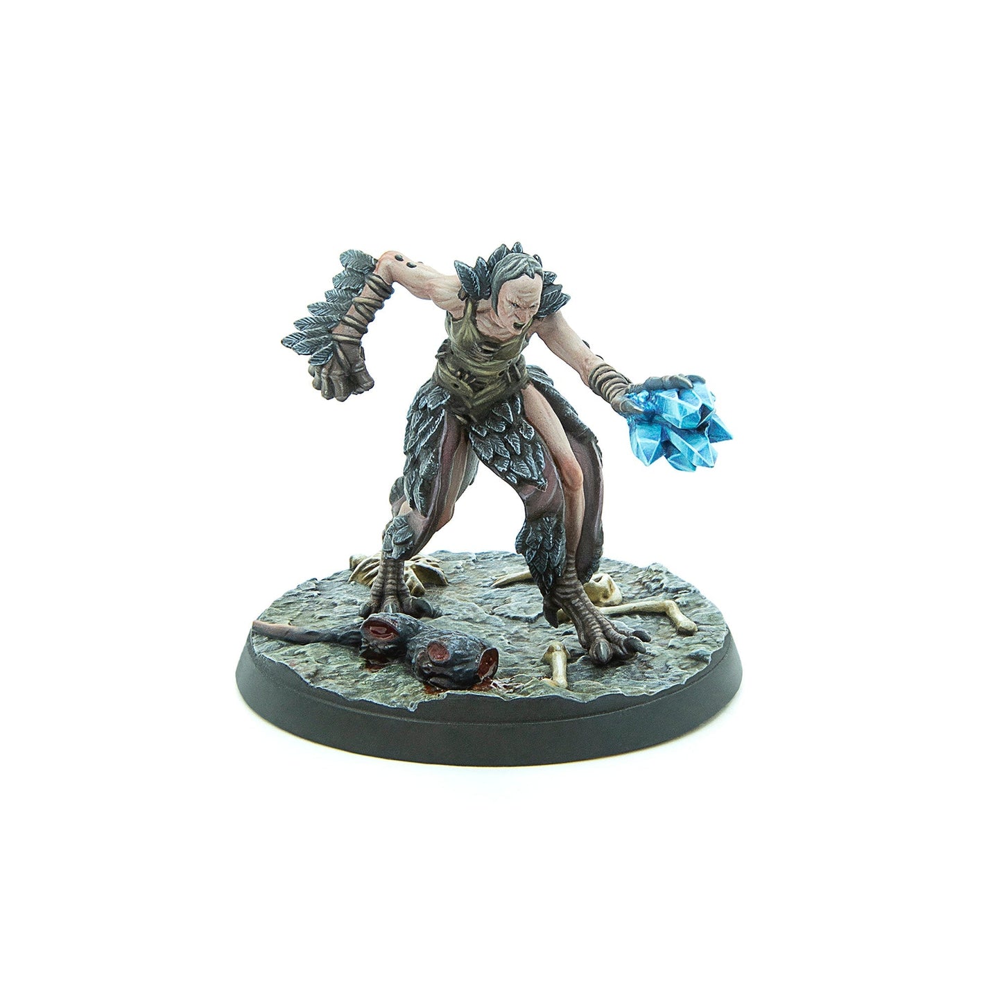 A gaunt, feathered creature miniature with clawed feet snarls, wielding a glowing blue crystal