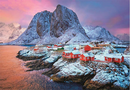 Red fishing village on snowy rocks by a bay, with massive snow-capped mountains under a pink-purple sky.