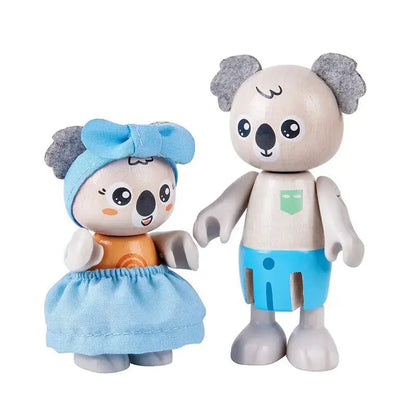 Two wooden koala toys stand side-by-side. The left one wears a blue dress and bow, the right wears blue shorts.