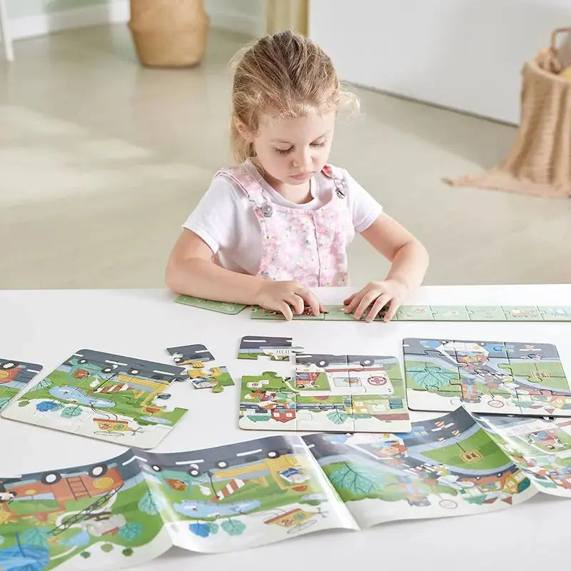 Young girl in a pink overall intently assembling road-themed jigsaw puzzles on a white table.