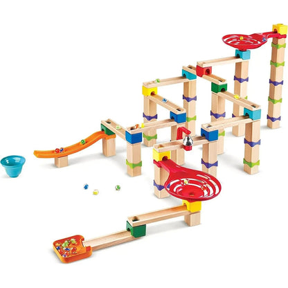 Colorful, stepped wooden marble run built from blocks and plastic tracks, with several glass marbles rolling