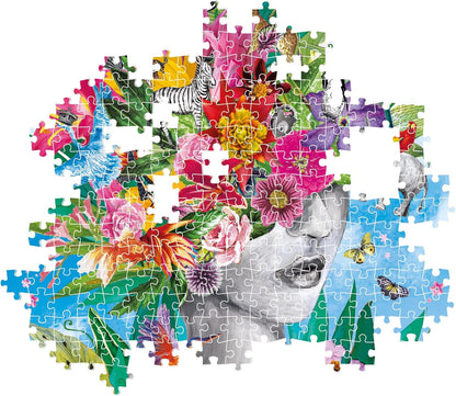 Unfinished jigsaw puzzle: grayscale woman's face crowned with vibrant flowers, animals, and leaves against a blue sky.