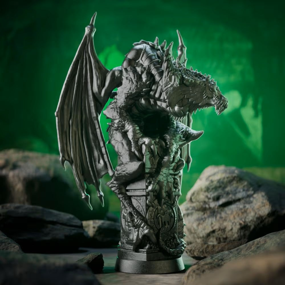 Dark grey dragon statue with large wings perched on an ornate pedestal, set against a glowing green background with rocks