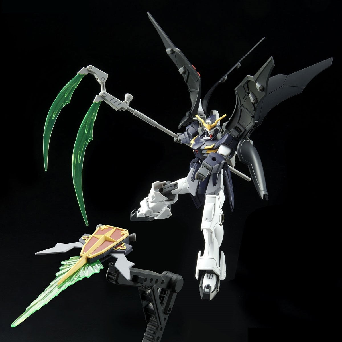Dark grey and white Gundam model with large black wings poses mid-action, wielding a glowing green beam scythe