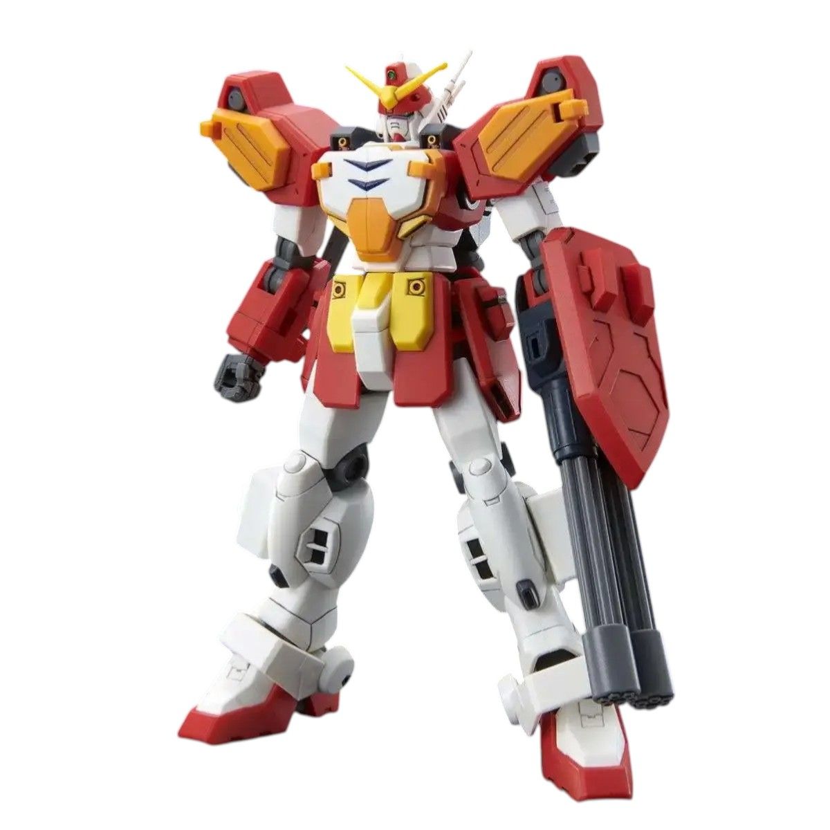 Red, white, and yellow Gundam model kit standing, armed with a multi-barreled gun and shield