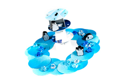 Board game pieces: Penguins on blue ice floes forming a ring, with a central tiered platform and clear ice gems