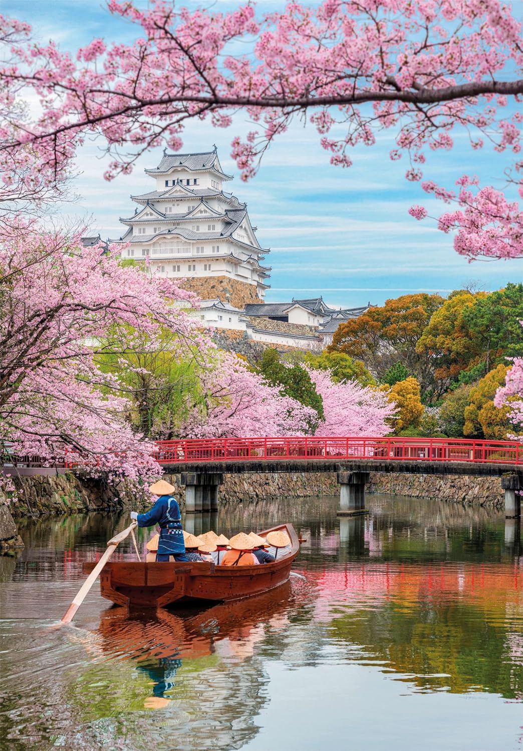 A person rows a boat on a river, framed by pink cherry blossoms, with the white Himeji Castle and a red bridge in the background.