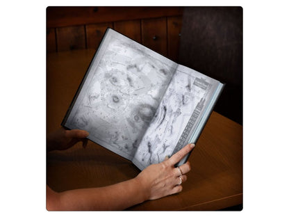 Hands hold open book displaying 3D grayscale celestial map with craters and stars on wooden table