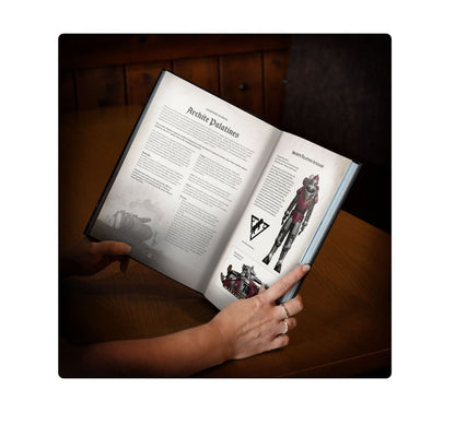 Hands hold an open rulebook titled "Archite Palatines," showing game text, a power-armored soldier, and a tank illustration
