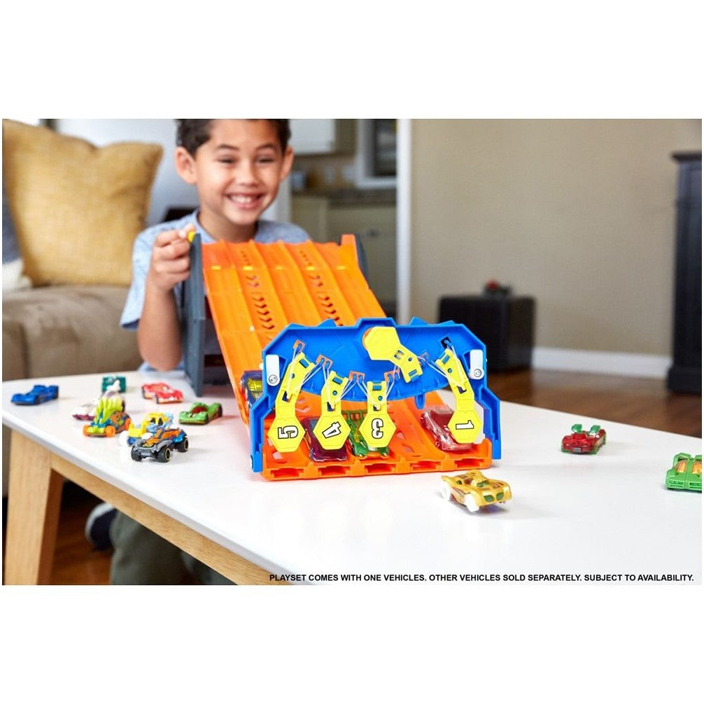 Happy boy launches Hot Wheels cars down an orange multi-lane race track