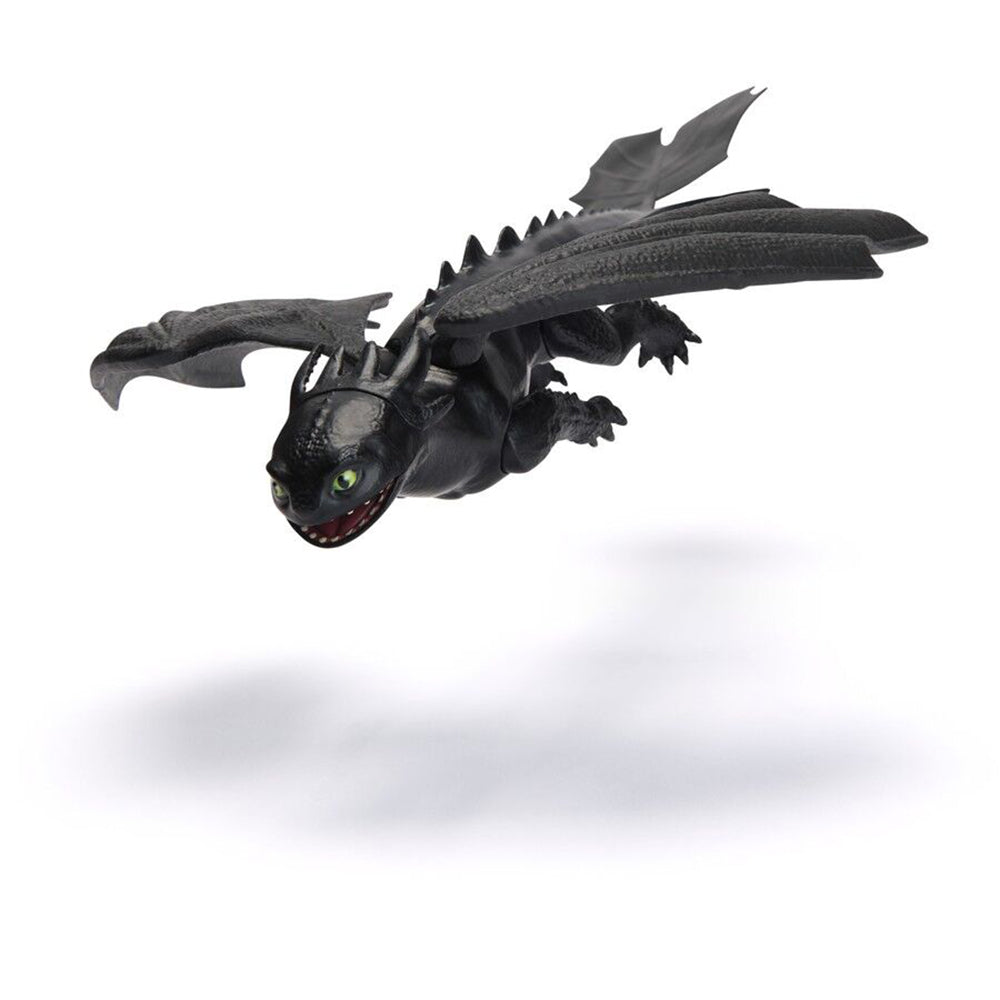 Black Toothless Night Fury dragon toy flying with green eyes, open mouth, and spread wings, casting a shadow