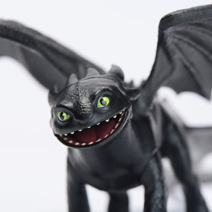 Black Toothless dragon figure with bright green eyes, wide open mouth showing teeth, and spread wings against a white background