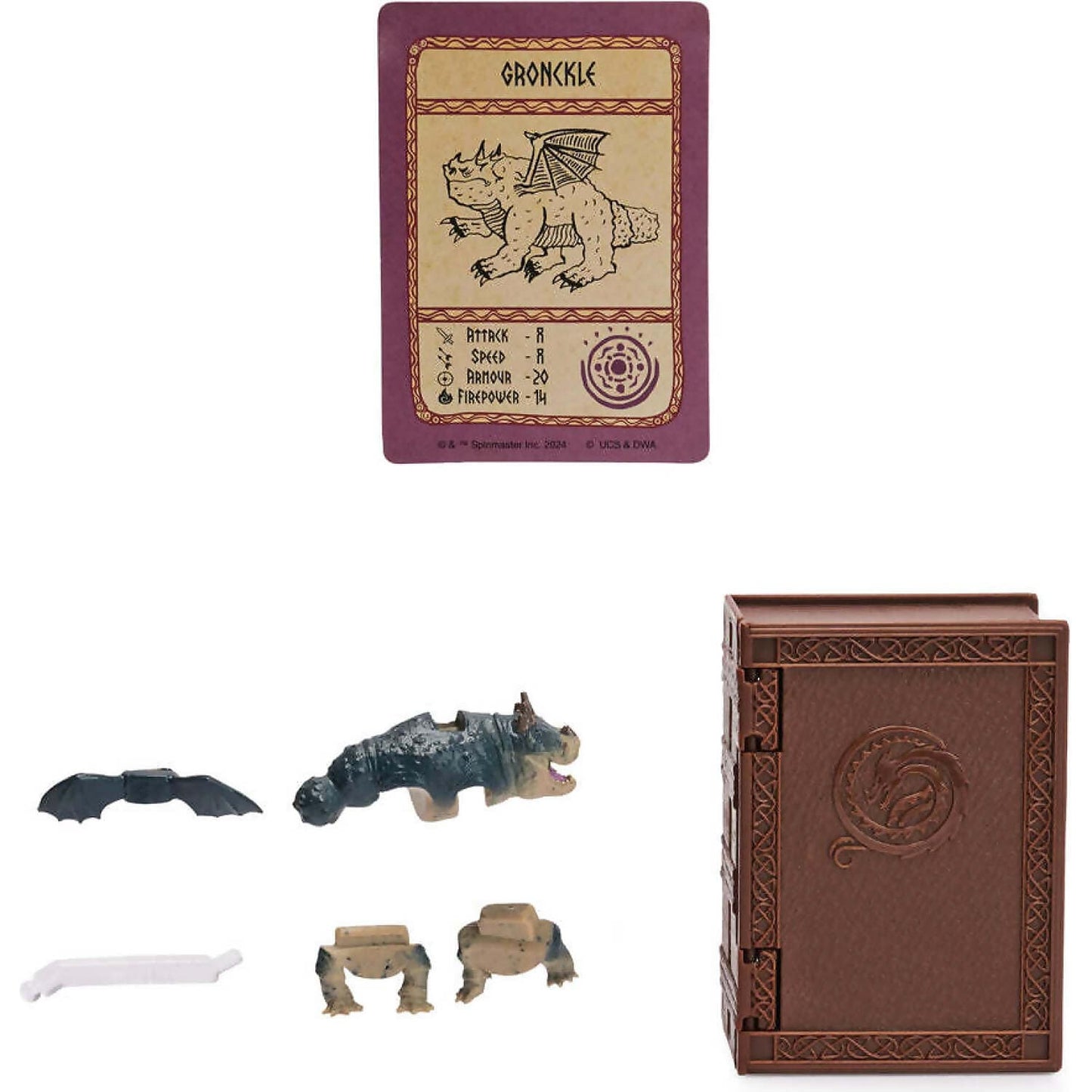 Purple Gronckle dragon trading card, unassembled dragon toy figure parts, and a brown book-shaped container with a dragon carving