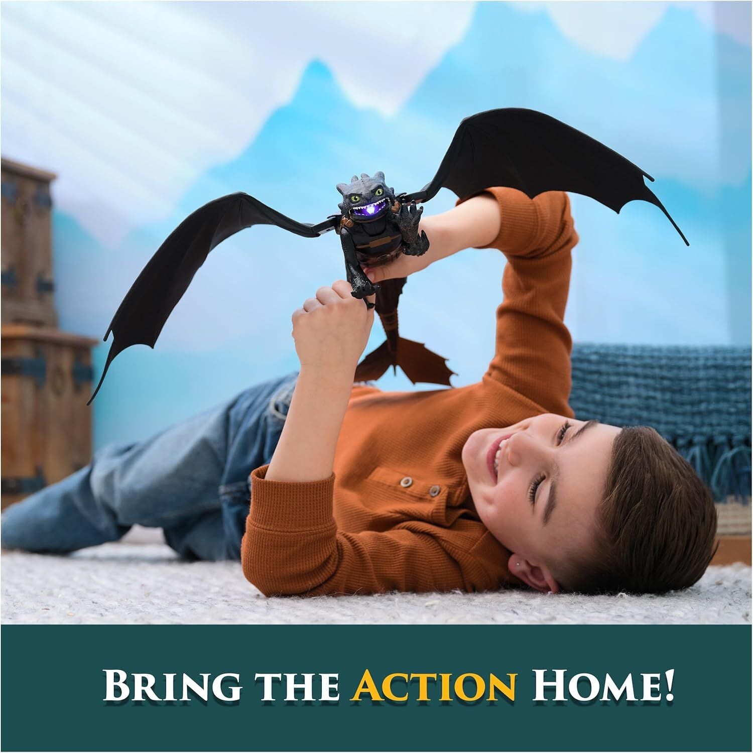 Smiling boy playing with a black Toothless toy dragon that has glowing purple eyes and mouth, lying on a white rug with a blue mountain backdrop