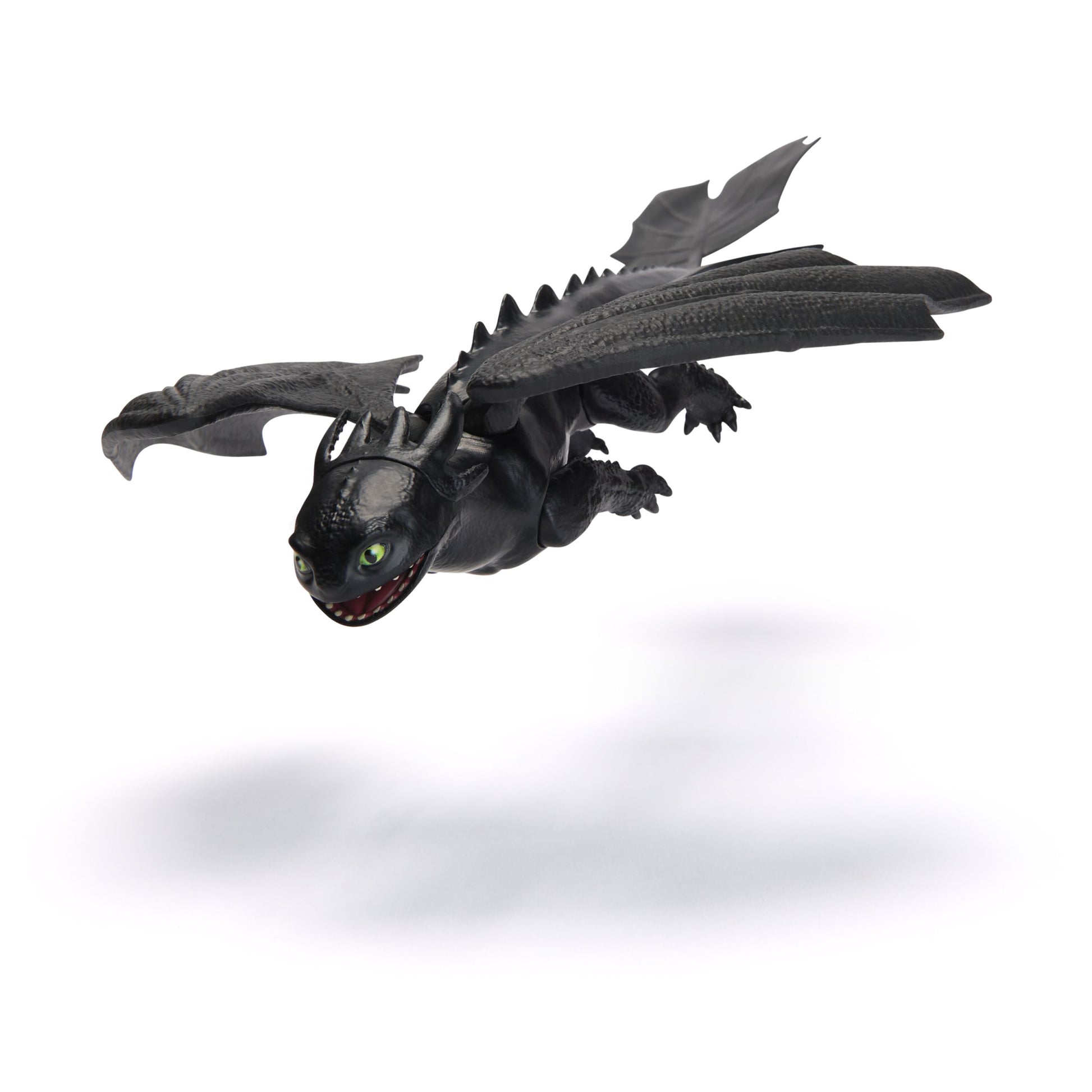 Black Toothless Night Fury dragon toy flying with green eyes, open mouth, and spread wings, casting a shadow