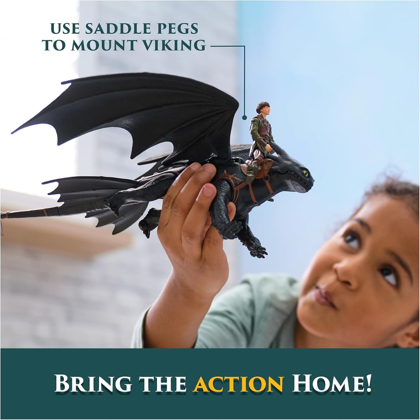 Young child holds a black Toothless dragon toy with Hiccup mounted on its back, looking up with fascination