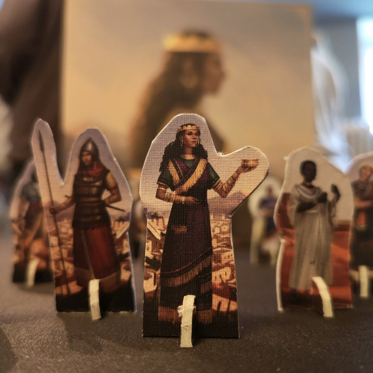 Cutouts depicting historical figures on a surface with one figure in the foreground wearing a crown and ornate clothing