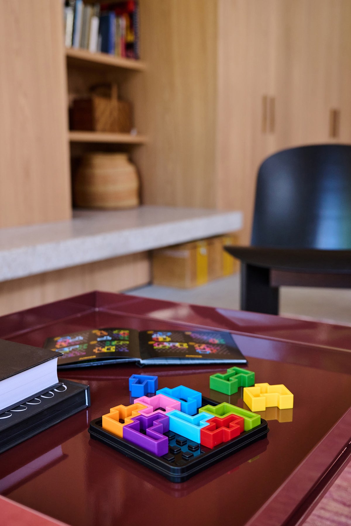 A colorful IQ Deluxe Square puzzle game partially assembled on a red table, next to an open instruction manual