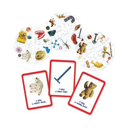 I Spy game pieces: circular boards full of tiny objects like a lion, car, and teddy bear. Three clue cards show a clock, rake, and teddy bear
