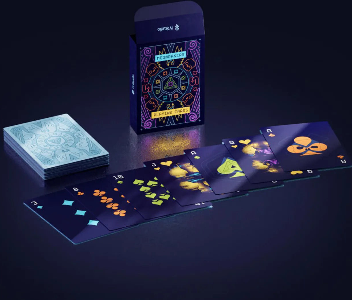 Neon Moonrakers playing card deck, showing the decorated tuck box, a face-down stack, and spread face cards