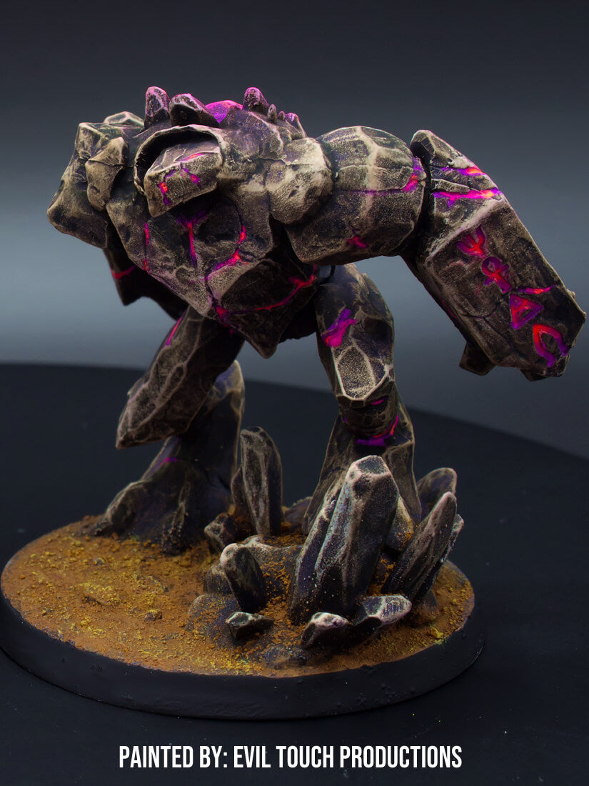 A dark stone golem miniature with bright pink glowing cracks stands on a rocky base