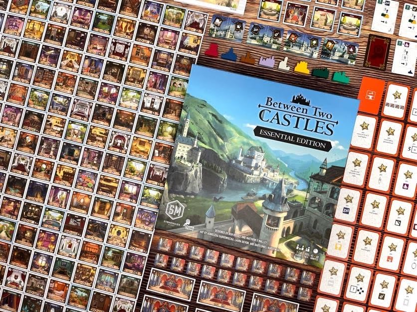 Board game box for Between Two Castles Essential Edition with game components spread out