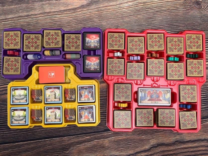Two board game box organizers filled with game pieces and cards