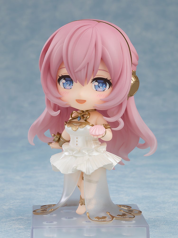 Smiling Nendoroid figure with pink hair, blue eyes, gold headphones, white dress with gold trim, holding a pink seashell