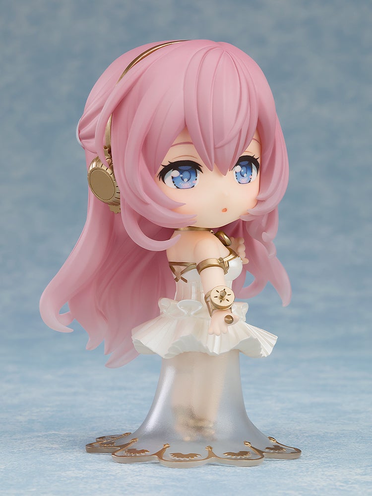 Chibi Megurine Luka figure with pink hair, blue eyes, gold headphones, wearing a white translucent gown, looking surprised