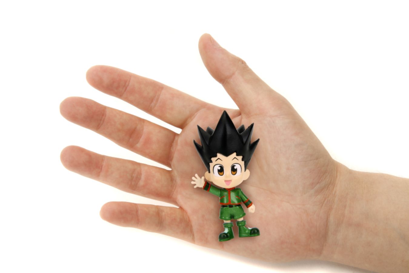 Gon Freecss chibi figure in green outfit resting in a human palm, showing its small scale