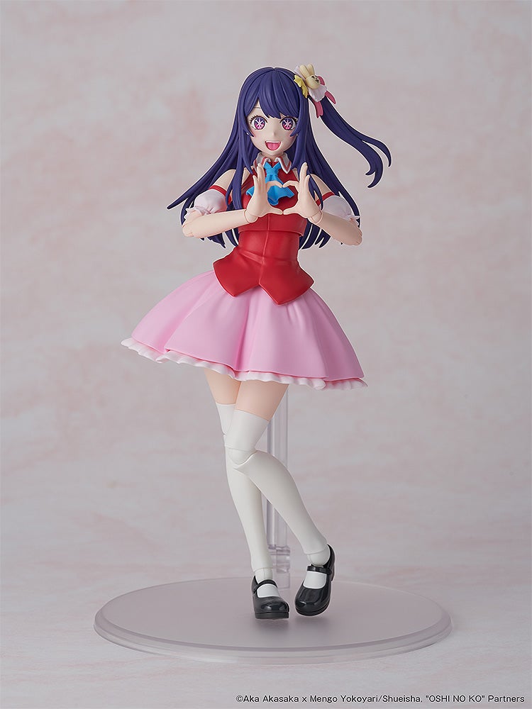 Articulated Ai Hoshino figure, with purple hair, star eyes, and pink dress, smiling while making a heart gesture