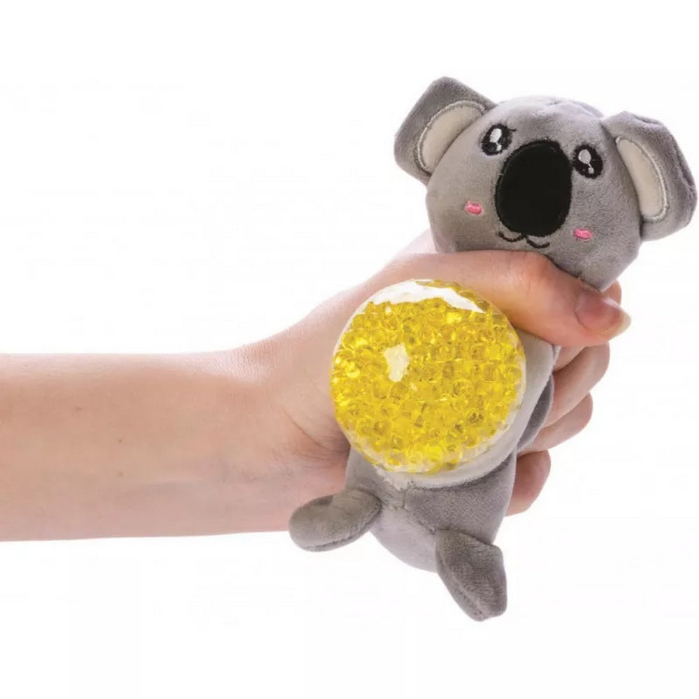 A hand squeezes a gray plush koala toy with a yellow beaded stress ball belly