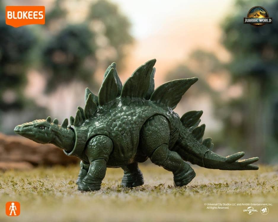 Green Jurassic World Stegosaurus action figure standing on grass in a jungle setting