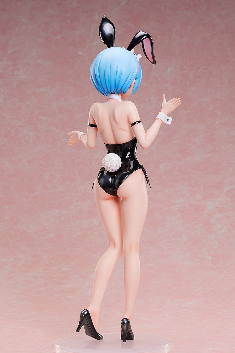 Rear view of a blue-haired anime figurine in a black bunny suit, with ears, a fluffy tail, and high heels, arms raised