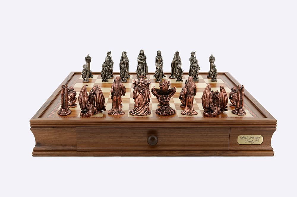 A Dal Rossi Evil Ring Metal Chessmen set, featuring fantasy figures and dragons, is displayed on a wooden chess board with a storage drawer