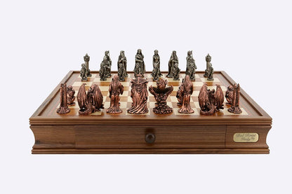 A Dal Rossi Evil Ring Metal Chessmen set, featuring fantasy figures and dragons, is displayed on a wooden chess board with a storage drawer