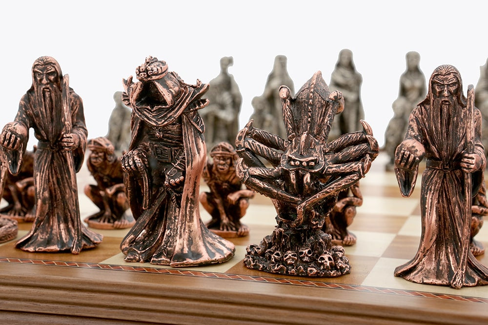 Close up of Dal Rossi Evil Ring Metal Chessmen, showing dark bronze fantasy figures like a wizard, a crowned hooded king, and a spider on a skull base on a chess board