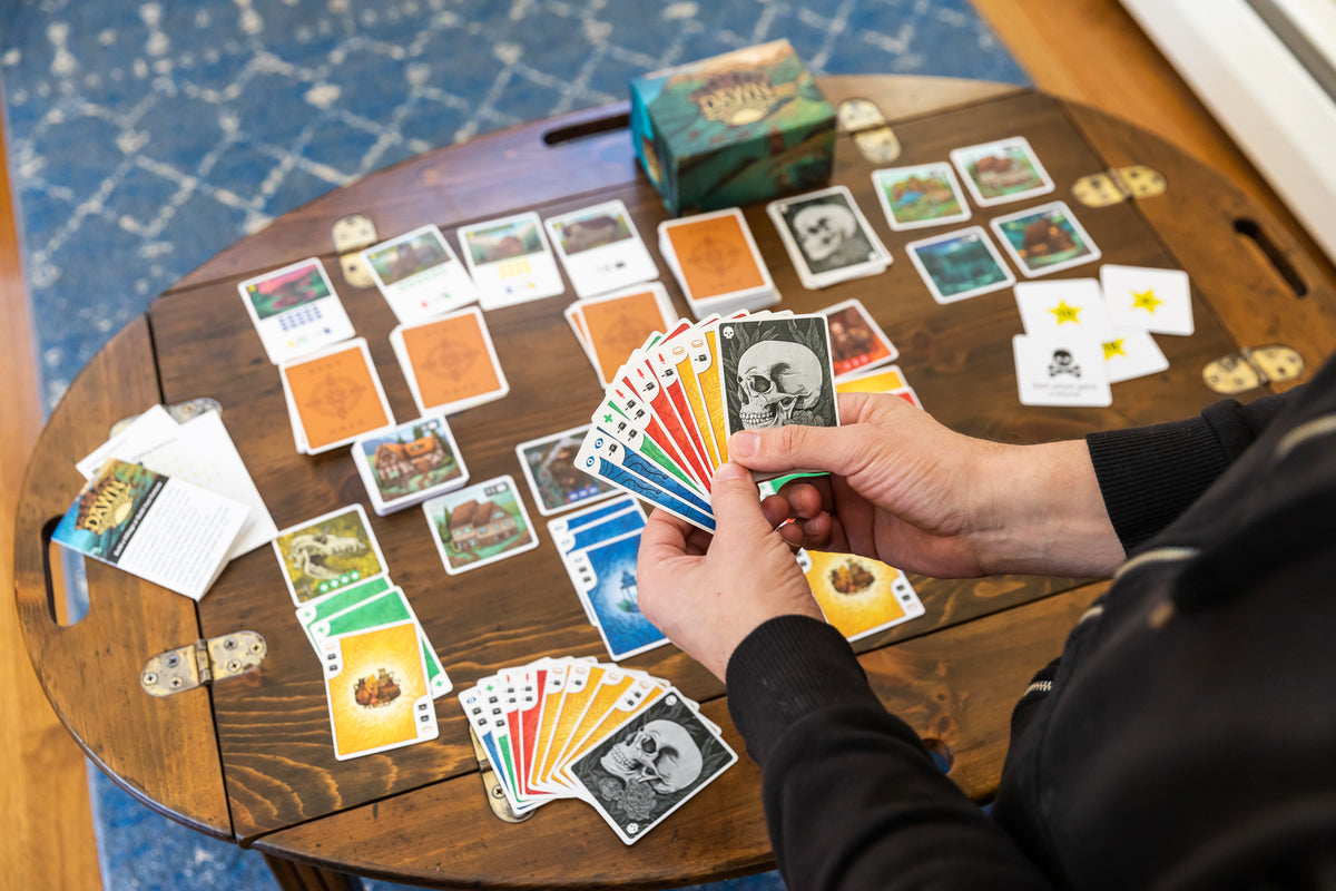 Candid lifestyle photo of players engaged in a session of Dawn, with the game prominently set on a table in a cozy indoor setting